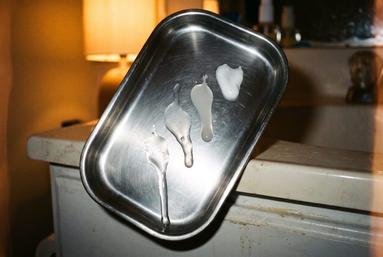 Four skincare drips run down a tilted steel tray at different speeds, from watery toner to thick cream