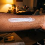 Two stripes of sunscreen on a deep brown forearm: one leaves a white cast, the other nearly vanishes